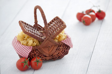 Cesta de mimbre con tomates cherry y pasta de espirales