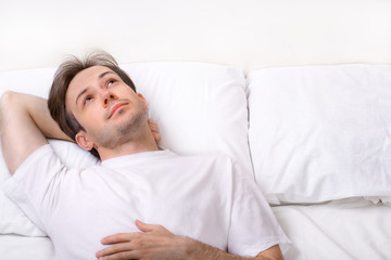 Thinking young man lying on bed