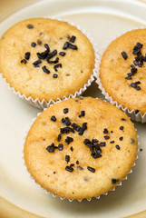 Freshly baked muffins in cups topped with chocolate .