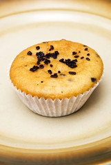 Freshly baked muffins in cups topped with chocolate .