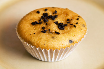 Freshly baked muffins in cups topped with chocolate .