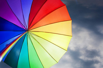 Rainbow umbrella on stormy sky background