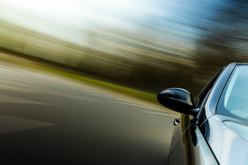 Front side mirror view of black car with heavy blurred motion.