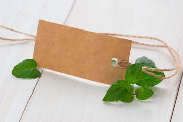 leaves of fresh mint with blank tag on wooden background