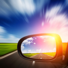 car mirror with blue sky above road