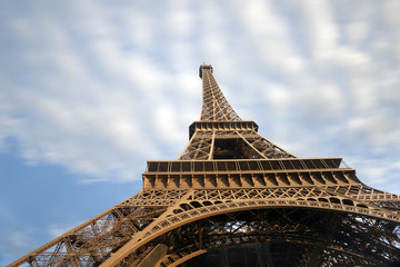 Eiffel tower detail with moving clouds on blue sky, Paris