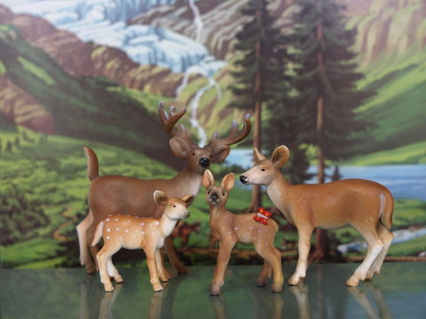 Modellrehe und -hirsch vor Alpenlandschaft