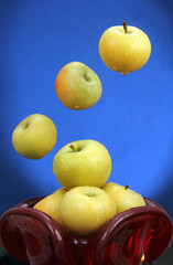 apples in a red glass vase.
