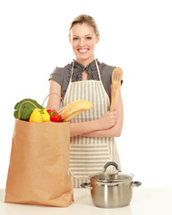 Woman in apron standing near table  with grocery bag