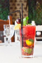 A delicious red cocktail with mint on a table.