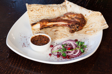 Juicy meat on the bone with onions, served with sauce.