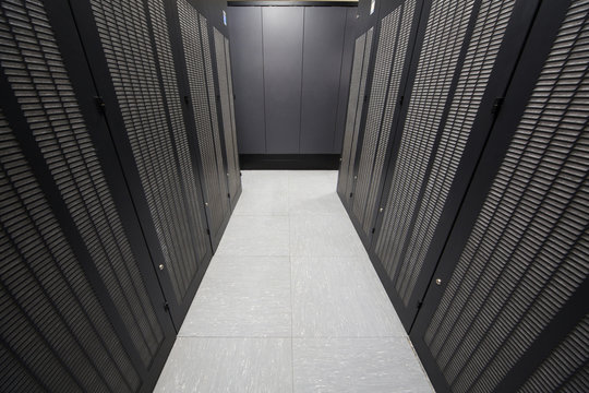 Telecommunication racks are symmetrically in corridor.