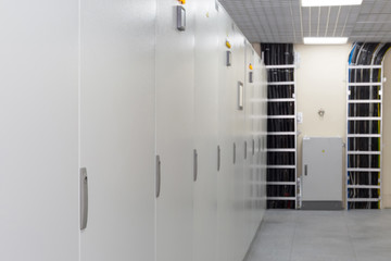 Rows of racks with equipment for telecom and cables.