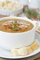 Mushroom soup in a bowl with croutons and thyme close-up