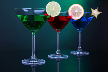 Alcoholic cocktails in martini glasses on dark green background