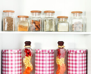 Beautiful white shelves with spices in glass bottles