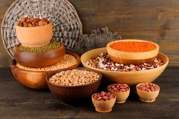 Different kinds of beans in bowls on wooden background