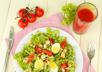 Caesar salad on white plate, on color wooden background