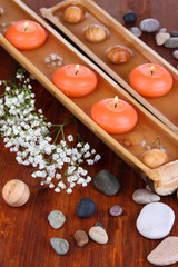 Beautiful candles in water on wooden table close-up