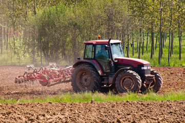 Red tractor with vibrocultor on fields side view