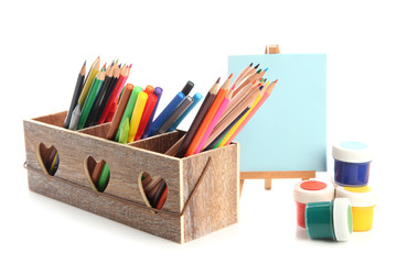Different pencils in wooden crate, paints and easel, isolated