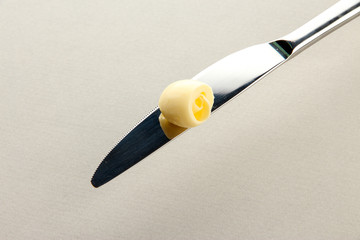 Butter curl on knife on grey background