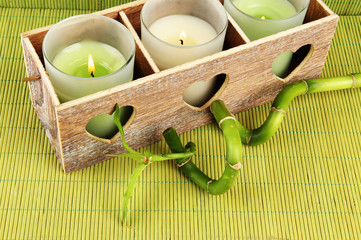 Wooden candlestick with candles and bamboo, on green mat
