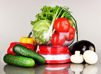 Fresh vegetables in scales on gray background