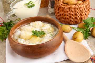 Tender young potatoes with sour cream and herbs in wooden bowl
