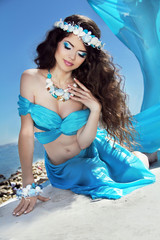 Long Healthy Hair. Beautiful brunette woman in blue silk luxury