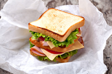 Sandwich with bacon and vegetables on wooden table
