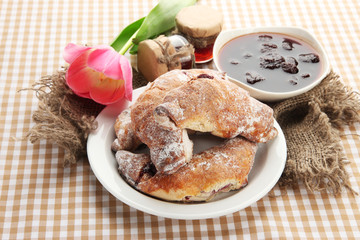 Taste croissants on plate and jam on tablecloth.