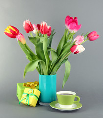 Fototapeta premium Beautiful tulips in bucket with gifts and cup of tea