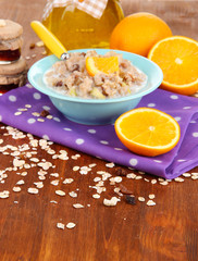 Useful oatmeal in bowl with fruit on wooden table close-up