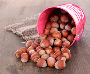 Overturned bucket with hazelnuts on wooden background