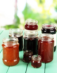 Tasty jam in banks on table on bright background