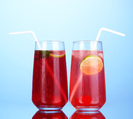 Two cherry cocktails with ice on dark blue background