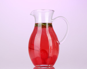 Cherry drink in pitcher on purple background.