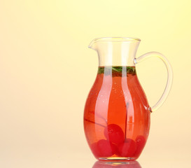 Cherry drink in pitcher on yellow background.