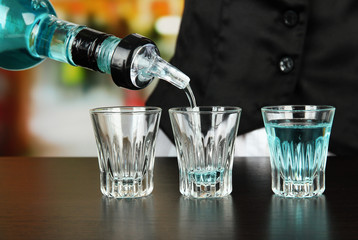 Barmen hand with bottle  pouring beverage into glasses,