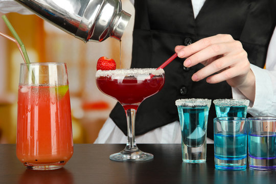 Barmen hand with shaker  pouring cocktail into glass,