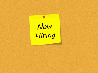 Now Hiring on Yellow Sticky note on Corkboard
