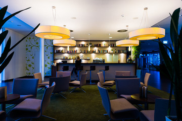 lonely girl sits alone at modern illuminated hotel bar