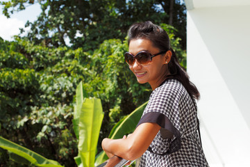 Young woman in sunglasses standing on a balcony and smiling