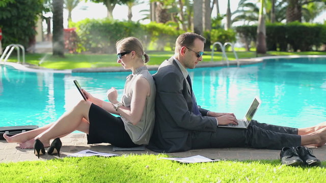 Business couple working together by the poolside 