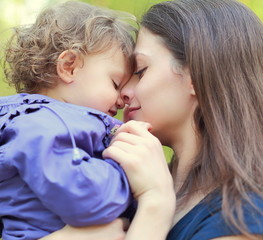Loving mother holding small happy girl and smiling. Closeup port