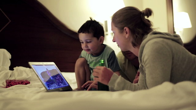 Happy family watching something on laptop in bedroom