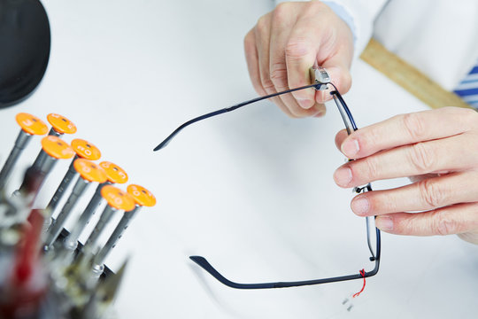 Hand eines Optikers repariert Brille