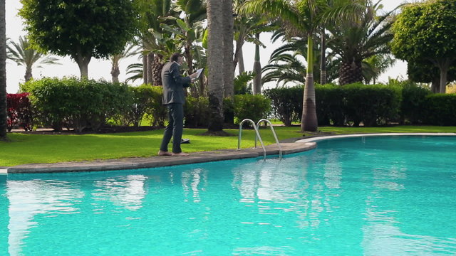 Angry businessman walking with cellphone by the poolside