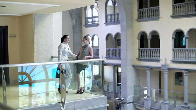 Two businesswoman standing on balcony in the hotel and chatting